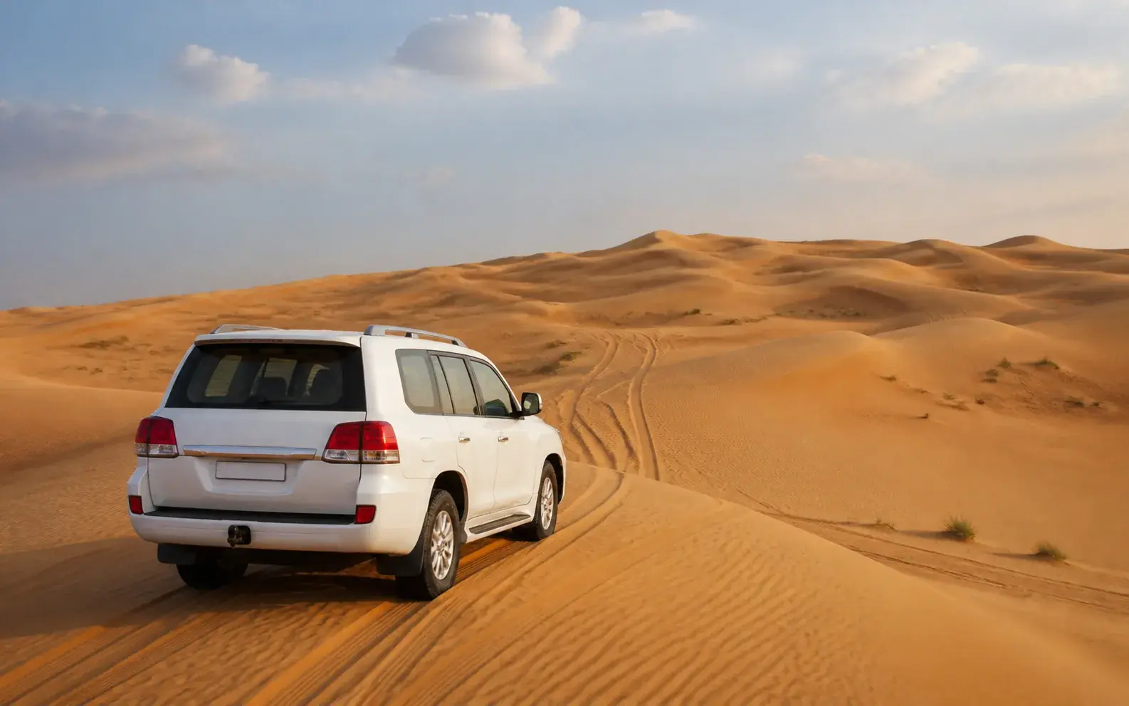White 4×4 crossing open dunes