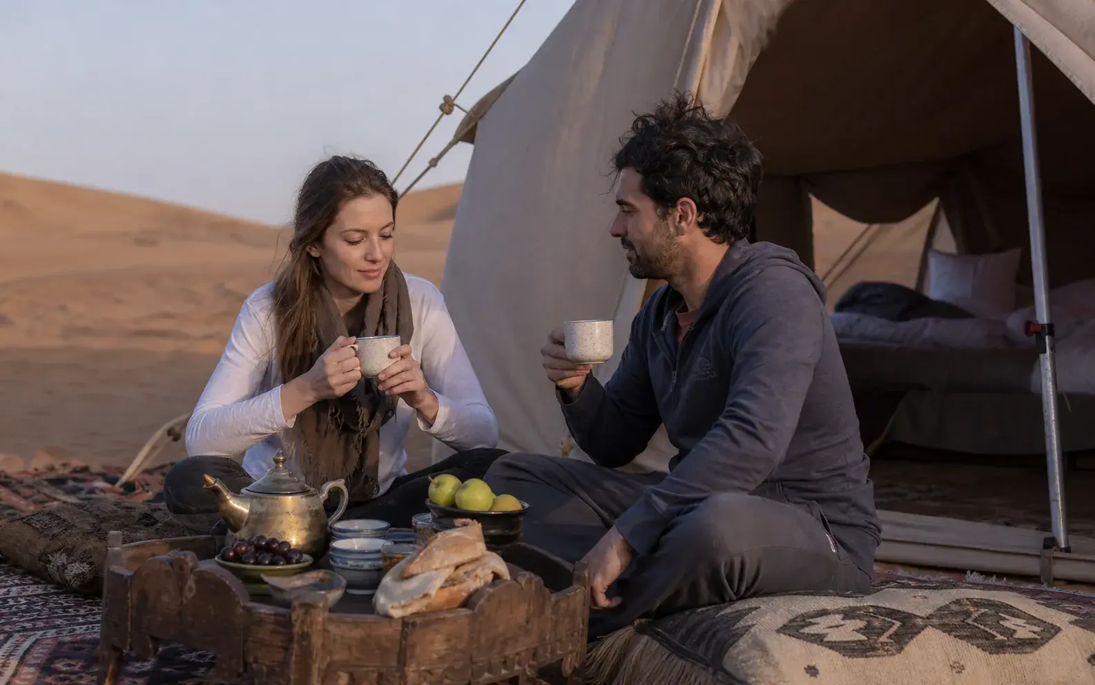 Comfortable prepared bedding inside a softly lit desert canvas tent